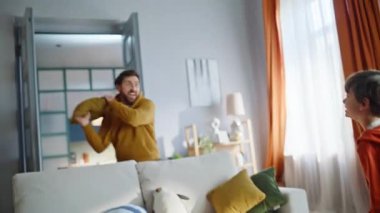 Evdeki halıları süpürüyor komik baba oyuncakları fırlatıyor, küçük yardımcı rahatsız ediyor. Aktif baba çocuk elektrikli süpürgeyle oyun oynayarak eğleniyor. Neşeli bir aile birlikte eğleniyor..