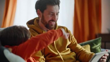 Baba çocuk elinde tablet web kamerasıyla kanepede otururken video görüşmesi yapıyor. Gülümseyen sakallı adam yakışıklı oğlu sanal buluşmada konuşurken görüntülü bilgisayar kamerası. Aile sohbeti.