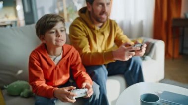 Babası evde oturan üzgün duygusal oğluyla video oyunu kazandı. Mutlu sakallı adam seviniyor online galibiyet, hayal kırıklığına uğramış küçük çocuk. Heyecanlı baba, oyun konsolunu tutarak zaferi kutluyor..