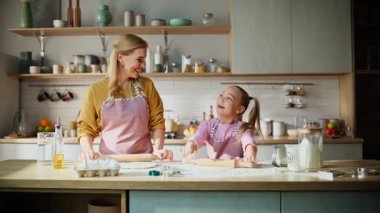 Cheerful family making dough at home closeup. Smiling mother talking with child at bright kitchen. Adorable preschooler girl doing bakery helping millennial mom. Homemade food little helper concept