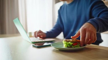 Erkek eller dizüstü bilgisayarda yazıyor ve mutfak tezgahında lezzetli sandviçler yiyor. Serbest çalışan biri kahvaltısını internetteki bilgisayarlara bakarak yapıyor. Uzaktan kumanda bilgisayarı izliyor.