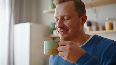 Taze espresso yudumlayan adam leziz kafein aromasının tadını çıkarıyor. Sabah kahvaltısında nefis kahve içen yakışıklı adam portresi. Ev içi rutin