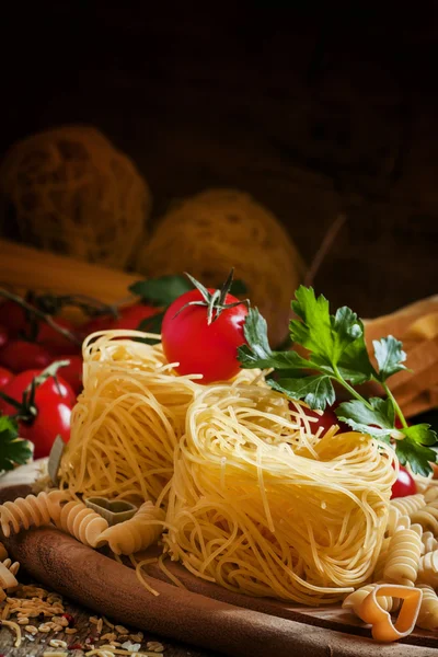 Dry Italian pasta Barbine in nests with cherry tomatoes and parsley — Stock Fotó