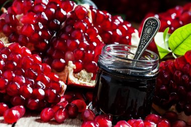 Homemade pomegranate jam in a glass jar with a spoon