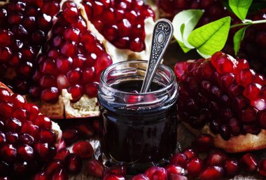 Homemade pomegranate jam in a glass jar with a spoon