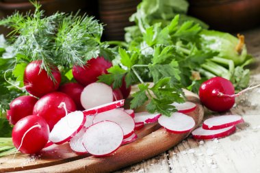 Slices of fresh radishes on a dark wooden background clipart