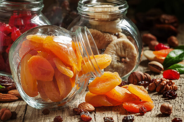 Dried apricots in a glass jar on a dark wooden background  