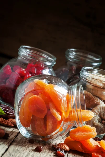 Dried apricots in a glass jar on a dark wooden background — Stock fotografie