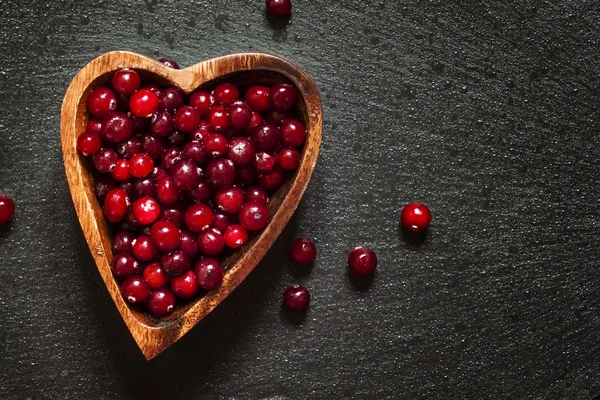 Verse cranberries in een houten kom in de vorm van een hart — Stockfoto