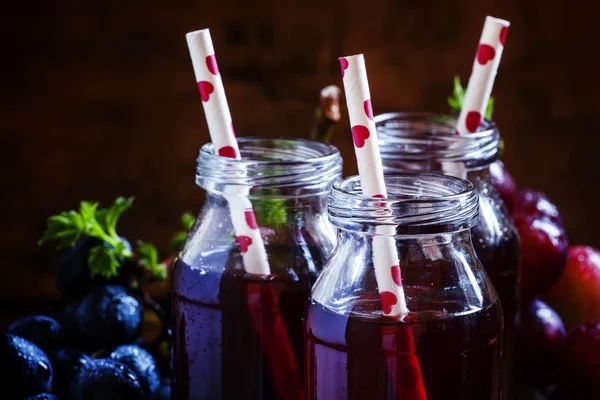 Jugo de uva oscura en botellas de vidrio con pajitas — Foto de Stock