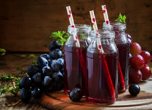 Jugo de uva oscura en botellas de vidrio con pajitas —  Fotos de Stock