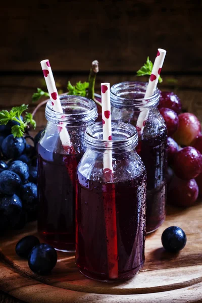 Темный виноградный сок в стеклянных бутылках с соломой — стоковое фото