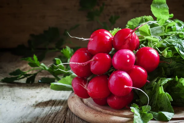 Racimo de rábanos rojos en una tabla de cortar — Foto de Stock