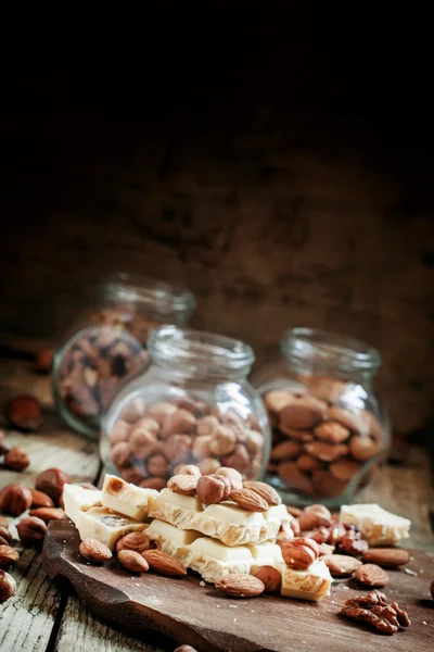 Finom fehér csokoládé, mandula, mogyoró, a régi, fából készült háttér — Stock Fotó