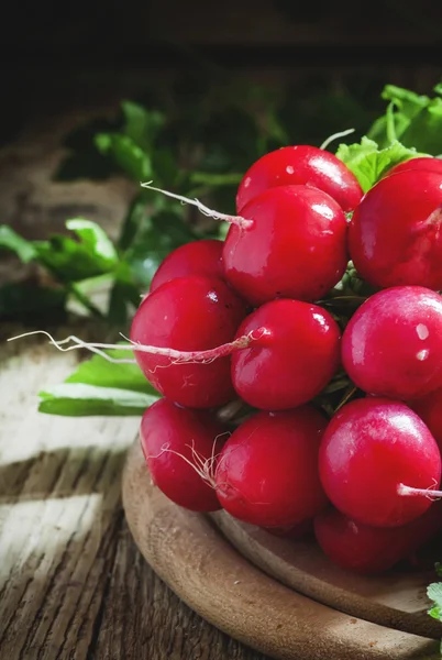 Racimo de rábanos rojos en una tabla de cortar — Foto de Stock