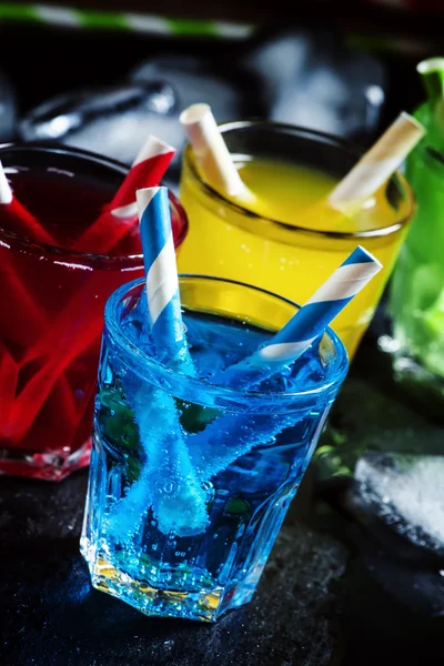 Bunte Cocktails mit Strohhalmen auf dunklem Hintergrund — Stockfoto