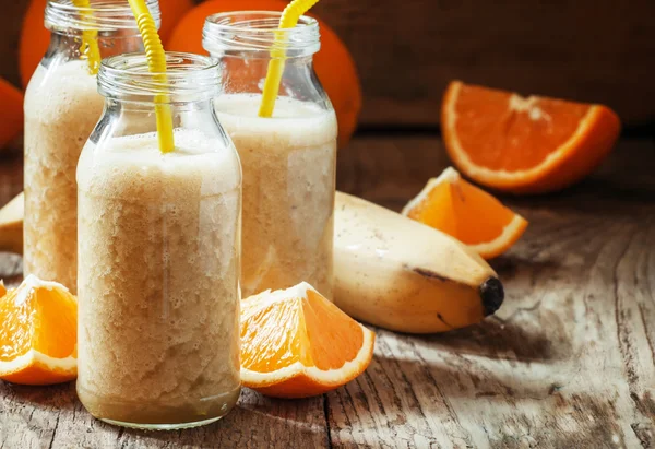 Orange-banana smoothie, small glass bottles with straws