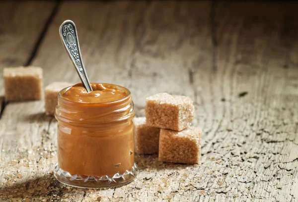 Sweet liquid caramel in a small jar — Stock Photo, Image