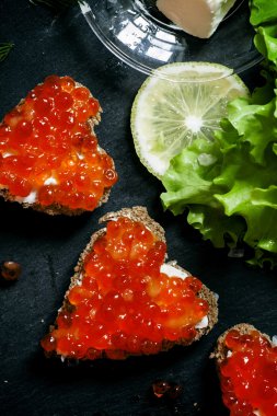 Sandwiches in the form of hearts with red salmon caviar  