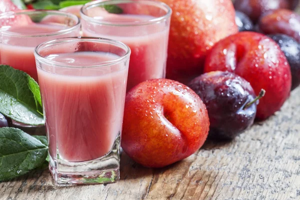 Plum and peach juice with pulp, spilled red and blue plums and peaches — Stock Photo, Image