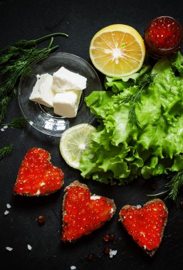 Sandwiches in the form of hearts with red salmon caviar  