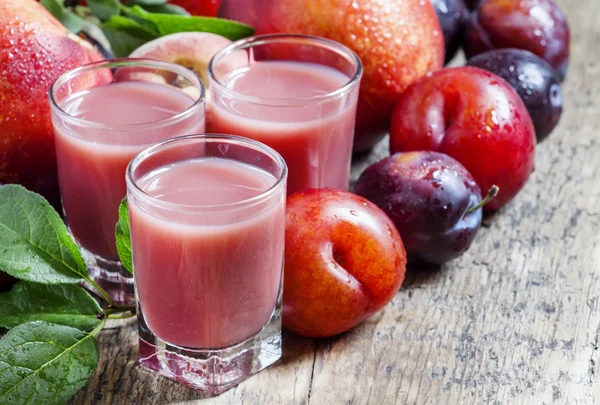 Plum and peach juice with pulp, spilled red and blue plums and peaches