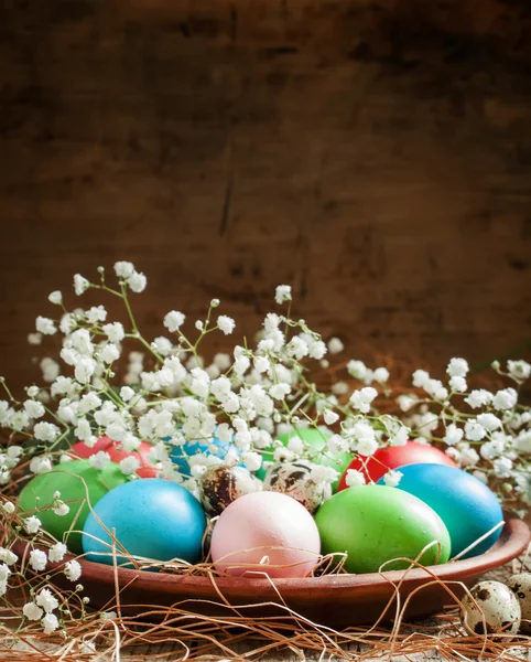 Многоцветные пасхальные яйца и перепелиные яйца на глиняной тарелке — стоковое фото