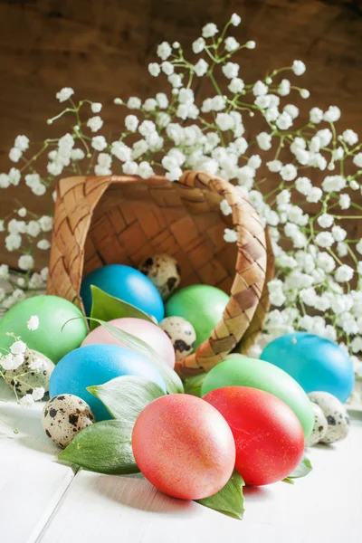 Многоцветные пасхальные яйца вылетают из плетеной корзины — стоковое фото