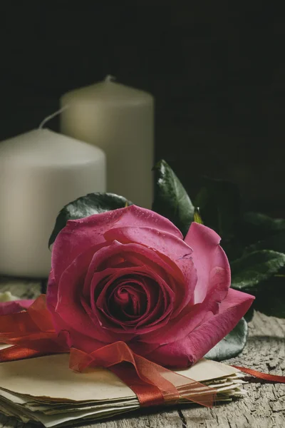 Винтажная композиция со свежей розовой розой, связкой старых букв — стоковое фото