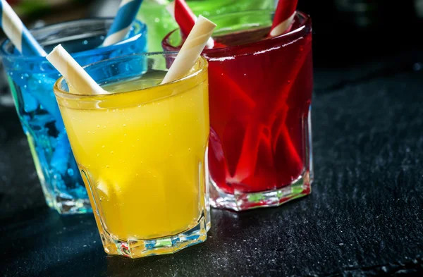 , gelbe, rote und grüne alkoholische Cocktails mit gestreiften Strohhalmen — Stockfoto