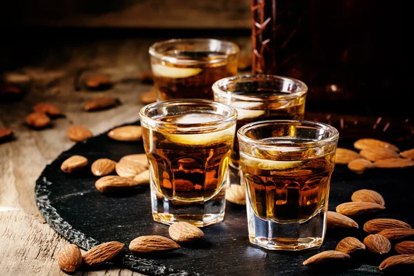 Cold whiskey with ice in a glass and a snack almonds — Stock Photo, Image