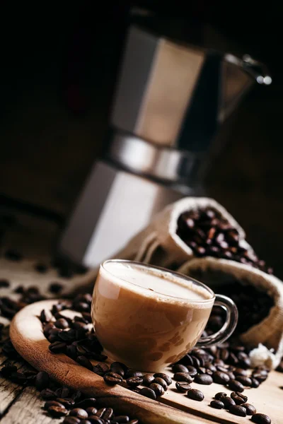 Черный кофе в чашке на фоне кофейных пакетиков с кофеваркой — стоковое фото