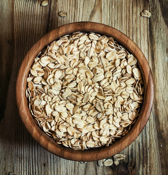 Oat flakes in a round bowl on the old wooden background — Stock Photo, Image