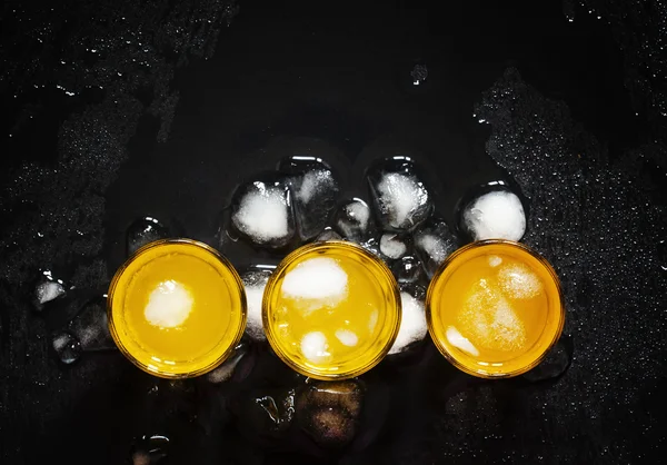 Gula cocktails med is på våt mörk bakgrund — Stockfoto