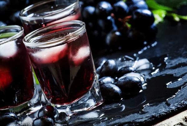 Jugo frío de uvas negras con hielo sobre fondo oscuro —  Fotos de Stock