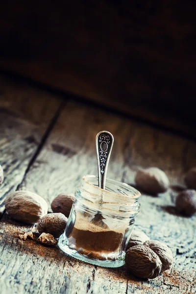 Nuez moscada molida en un frasco y nueces enteras — Foto de Stock