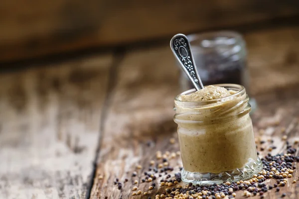 Mostaza en un frasco de vidrio y semillas negro y amarillo — Foto de Stock