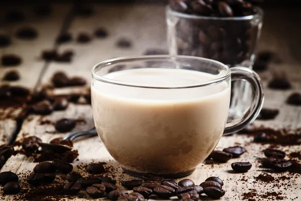 Glass cup of coffee with milk, spilled grain and ground coffee — Stock Photo, Image