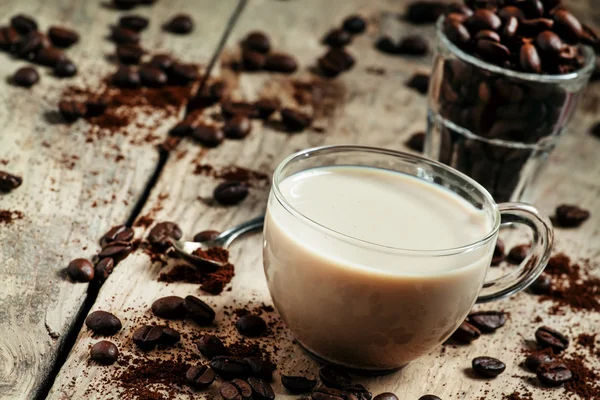 Tasse en verre de café avec lait, grains renversés et café moulu — Photo