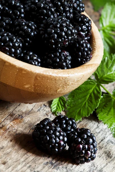 Schöne reife schwarze Brombeeren in Holzschale mit Blättern — Stockfoto