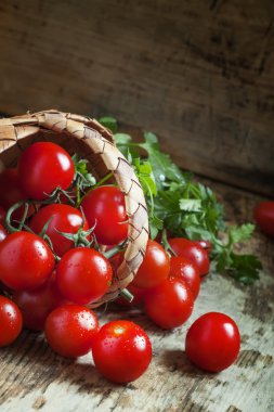 Küçük kırmızı kiraz domates bir hasır sepet dışarı dökmek 