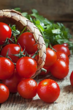 Küçük kırmızı kiraz domates bir hasır sepet dışarı dökmek 