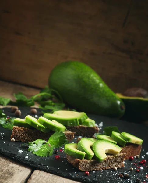 Сэндвичи с авокадо, черным ржаным хлебом и специями — стоковое фото
