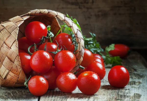 Küçük kırmızı kiraz domates bir hasır sepet dışarı dökmek — Stok fotoğraf