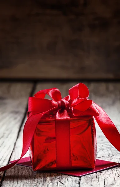 Caja de regalo roja atada con una cinta escarlata con lazo —  Fotos de Stock