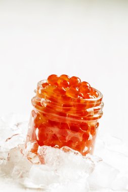 Kırılmış buz üzerinde cam kavanozda kırmızı somon havyar  