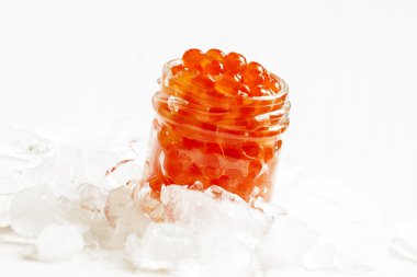Kırılmış buz üzerinde cam kavanozda kırmızı somon havyar  
