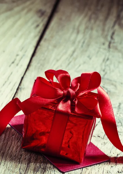 Caja de regalo roja atada con una cinta escarlata con lazo —  Fotos de Stock