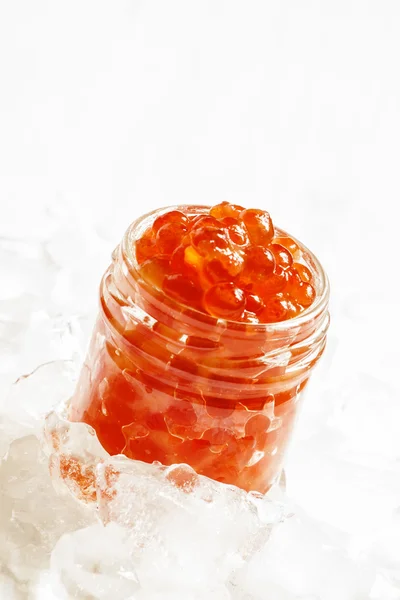 Caviale di salmone rosso in un barattolo di vetro su ghiaccio tritato — Foto Stock