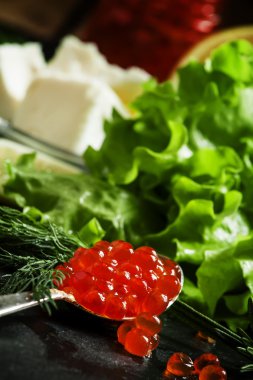 Bir gümüş kaşık siyah bir taş zemin üzerine kırmızı somon havyar  